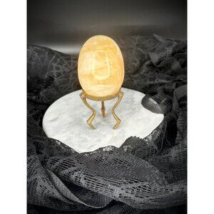 This is a polished yellow onyx gemstone egg on a brass stand